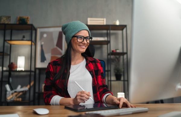 A happy female video editor works indoors in creative office studio.