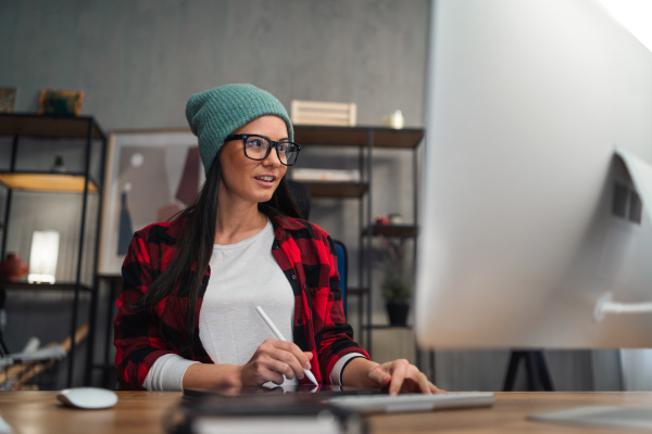 A happy female video editor works indoors in creative office studio