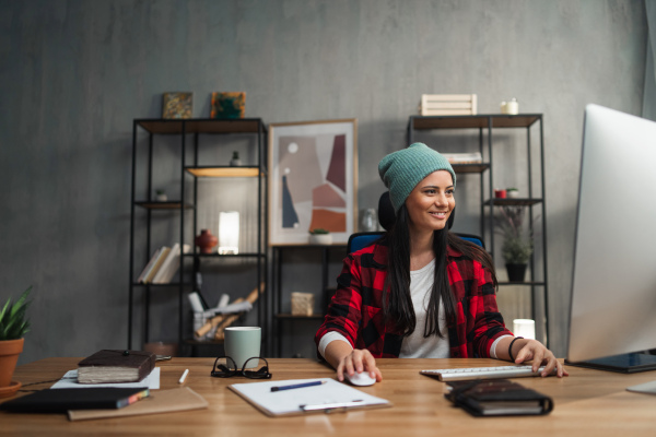 A happy female video editor works indoors in creative office studio.