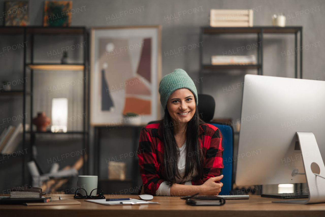 A happy female video editor works indoors in creative office studio, looking at camera.