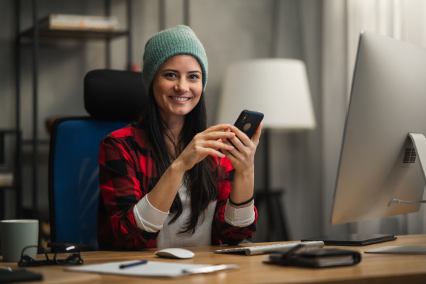 A happy female video editor works indoors in creative office studio, looking at camera.