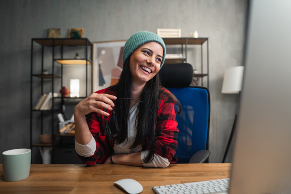 A happy female video editor works indoors in creative office studio.