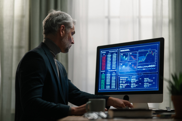 A mature businessman working on computer indoors in office.