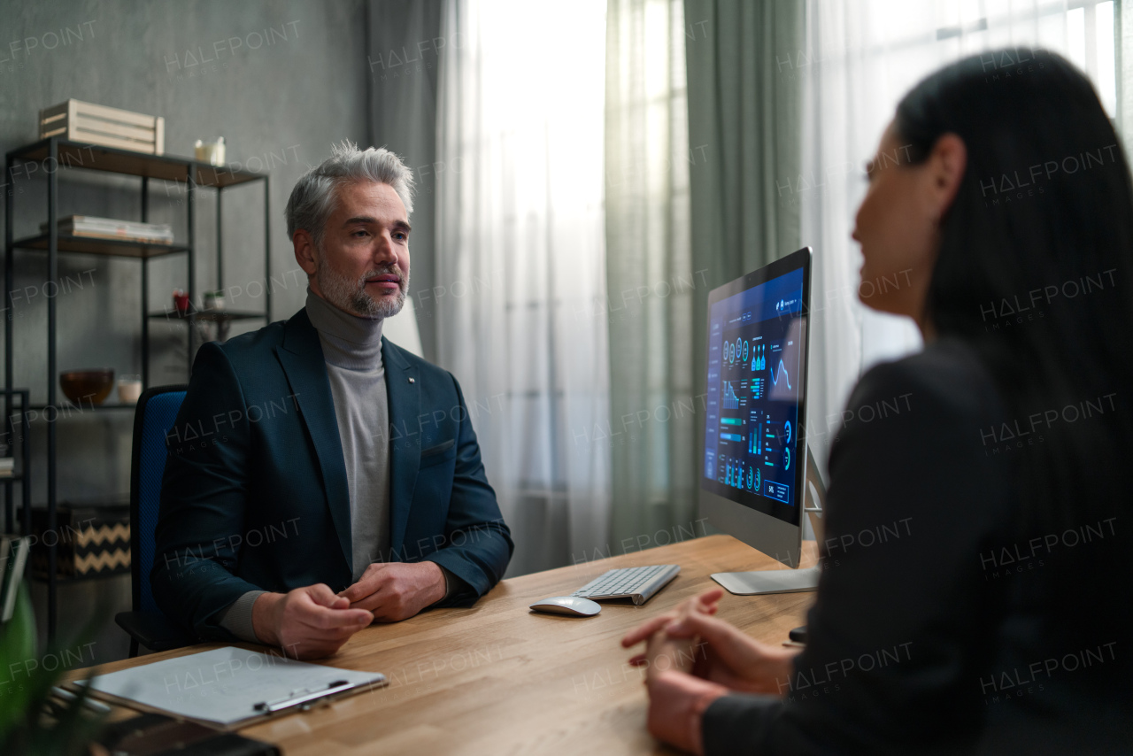 A mature financial advisor consulting with his client indoors in office.