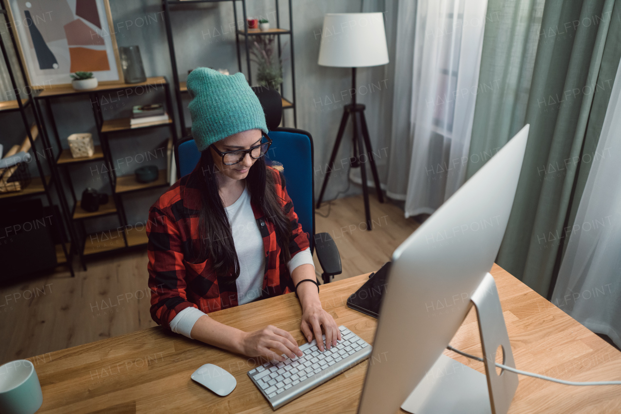 A high angle view of happy female video editor works indoors in creative office studio.