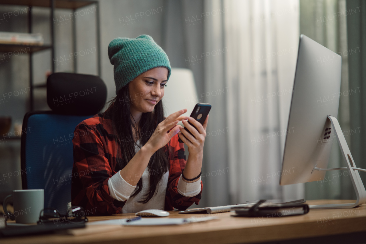 A happy female video editor using smartphone indoors in creative office studio.