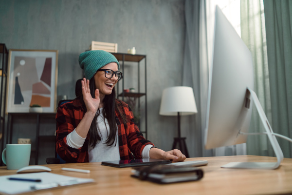 A female video editor having a vide call with her colleagues indoors in creative office studio.