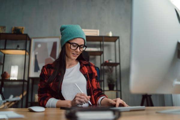 A happy female video editor works indoors in creative office studio.