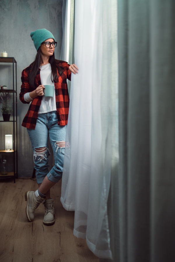 A mid-adult hipster woman having coffee break indoors in creative office studio.