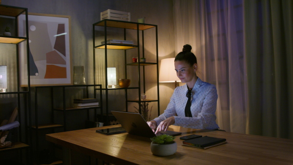 A mid adult business woman working on laptop in office at night.