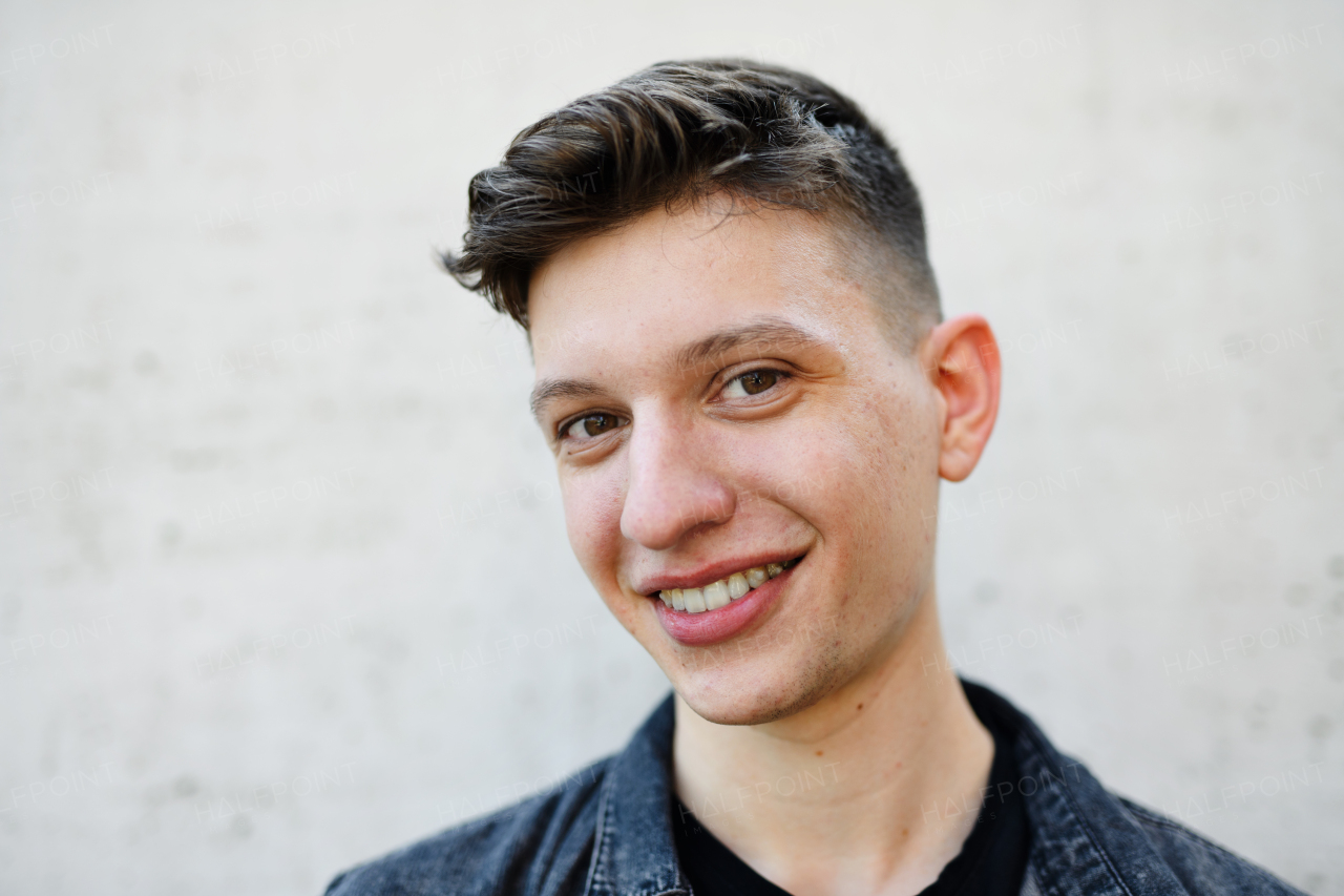 A portrait of young man standing outdoors against white background, looking at camera.