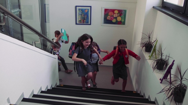 A group of cheerful small school kids running up the stairs.