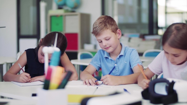 A group of small school kids in class, drawing.