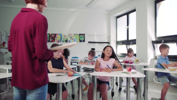 A teacher among small school children on the lesson, explaining.