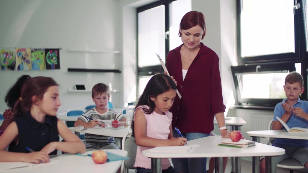 A teacher among small school children on the lesson, explaining.