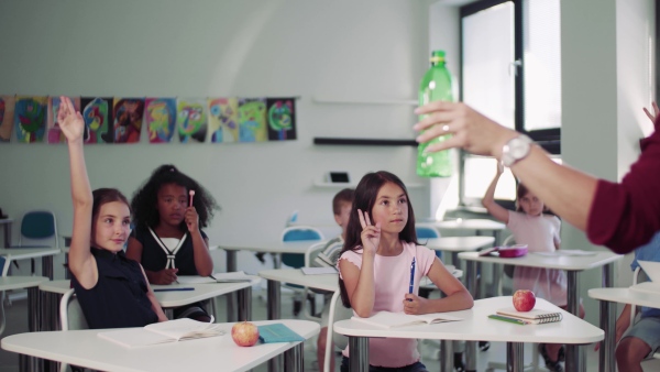 A teacher with small school kids in classroom learning about ecological waste separation.