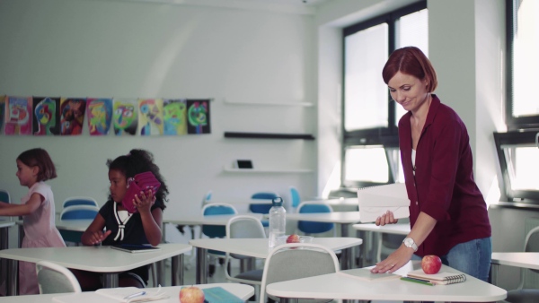 A teacher collecting exercise books after the lesson in school.