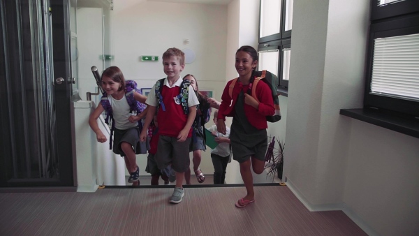 A group of cheerful small school kids running up the stairs. Slow motion.