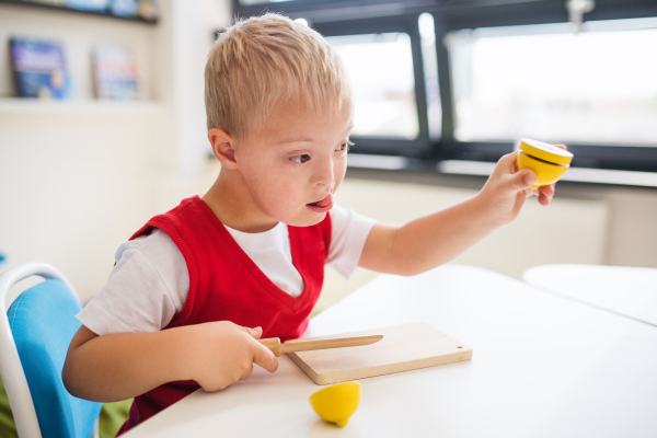 A happy down-syndrome school boy sitting at the desk in the classroom, learning.