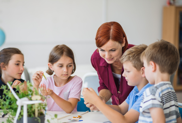 A group of small school kids with teacher in science class learning about environment.