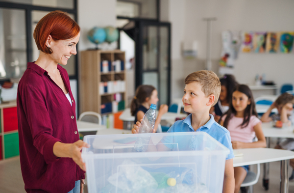 A teacher with small school kids in classroom learning about ecological waste separation.