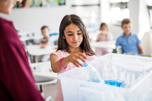 A teacher with small school kids in classroom learning about ecological waste separation.