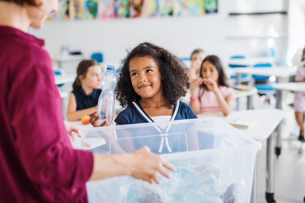 A teacher with small school kids in classroom learning about ecological waste separation.