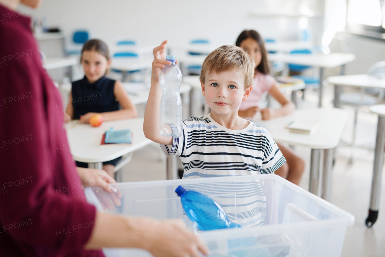 A teacher with small school kids in classroom learning about ecological waste separation.