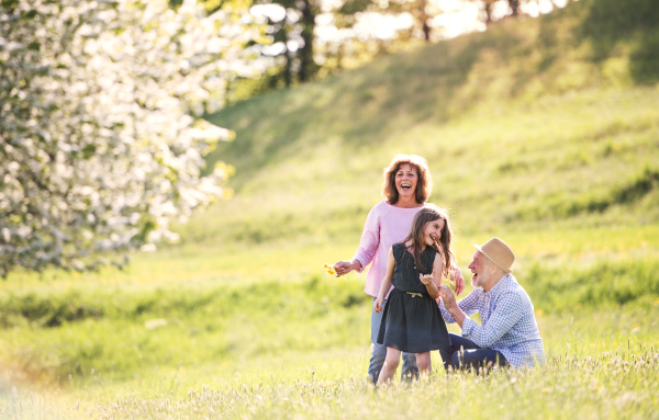 Senior couple with granddaughter outside in spring nature, laughing. Copy space.