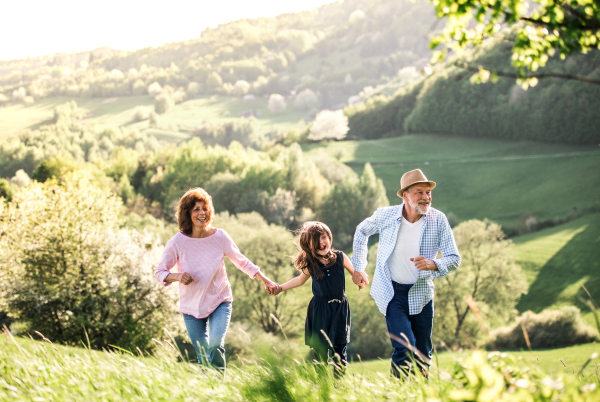 Senior couple with granddaughter walking outside in spring nature. Copy space.