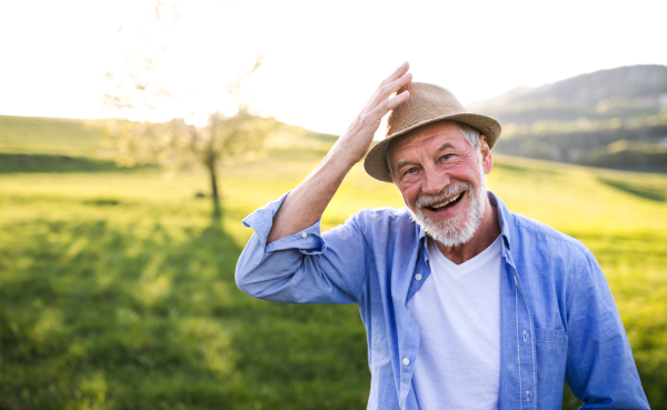 Portrait of a happy senior man with denim shirt in spring nature at sunset. Copy space.