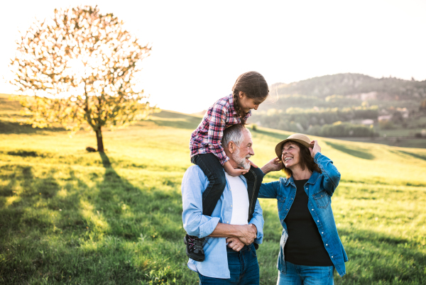 Happy senior couple with granddaughter outside in spring nature, having fun.