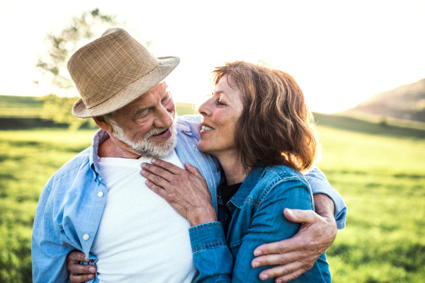 Happy senior couple outside in spring nature, hugging.