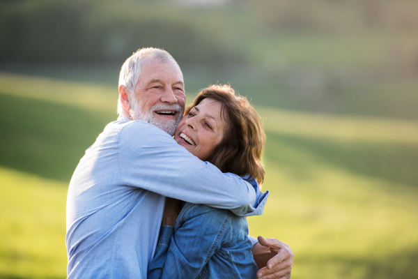 Happy senior couple outside in spring nature, hugging.