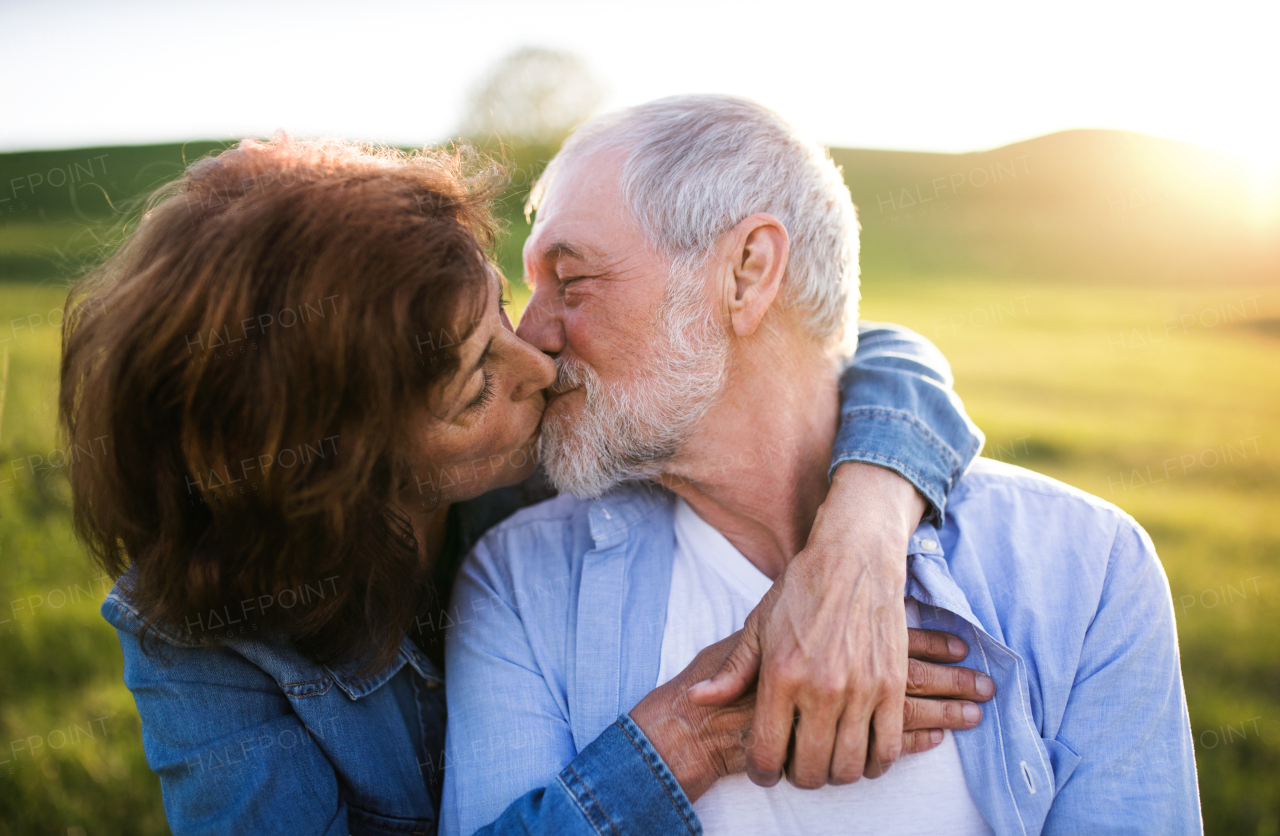 Happy senior couple outside in spring nature, kissing.