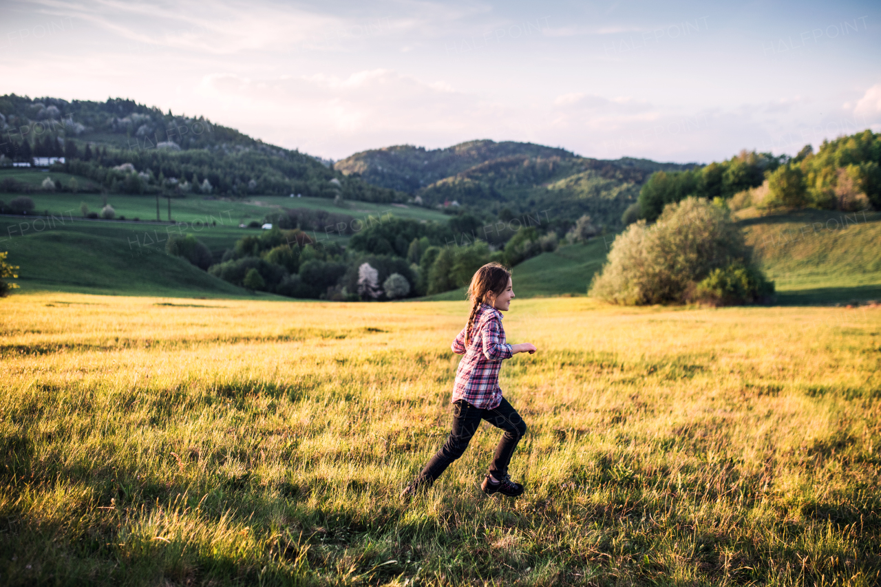 A happy small girl having fun outside in nature, running.