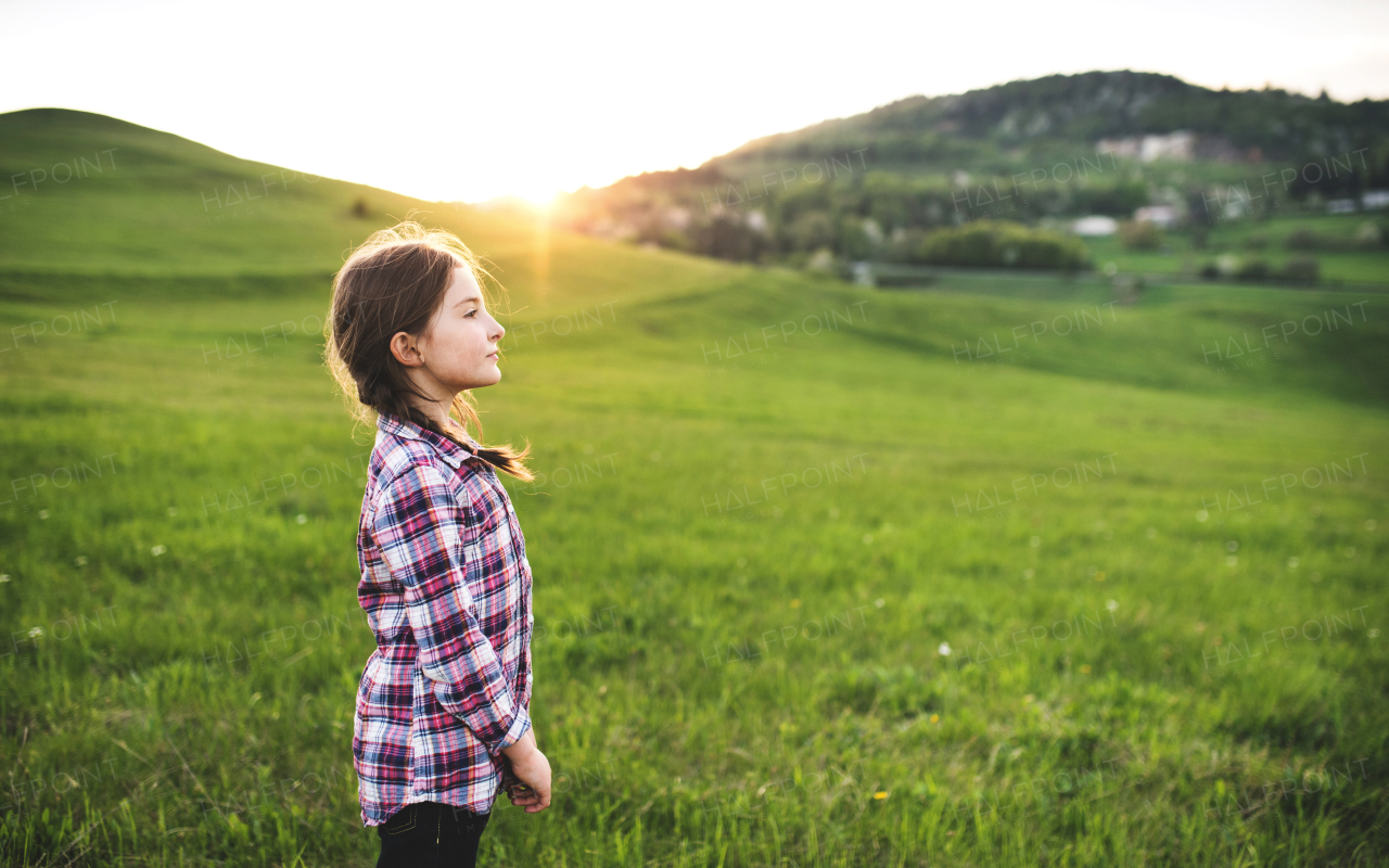 A happy small girl standing outside in nature. Copy space.