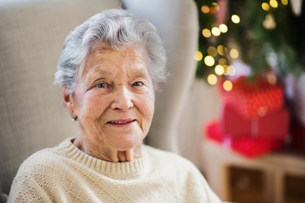 A portrait of a lonely senior woman in wheelchair at home at Christmas time.