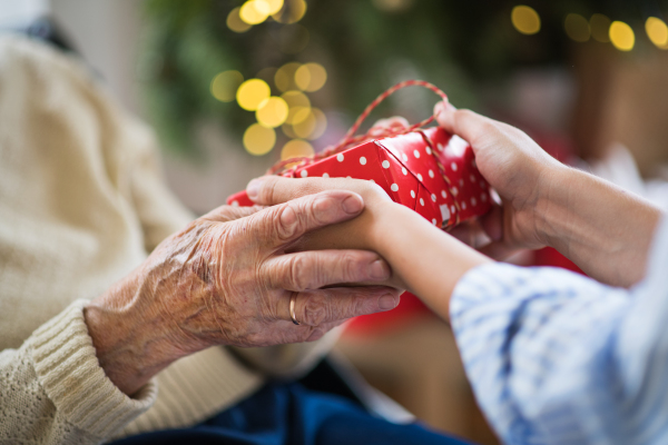 Close-up of hands of senior and young woman holding a present at Christmas time.