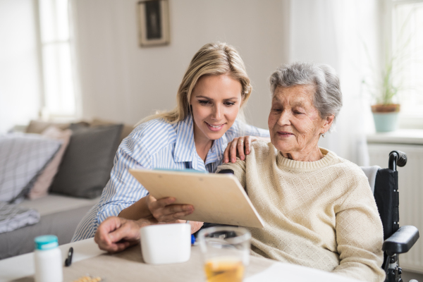 A young health visitor measuring a blood pressure of a senior woman in wheelchair at home.