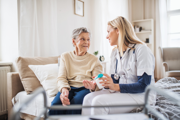 A young health visitor explaining a senior woman how to take medicine and pills.