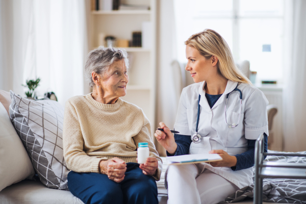 A young health visitor explaining a senior woman how to take medicine and pills.