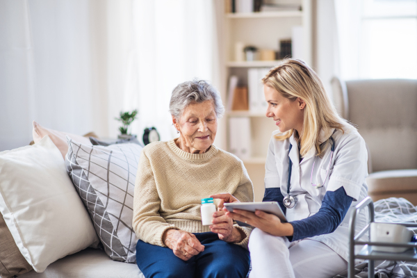 A young health visitor explaining a senior woman how to take medicine and pills.