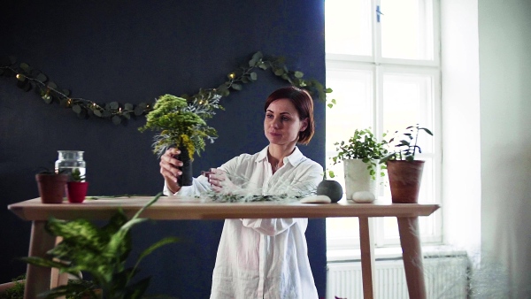 A young creative woman arranging flowers in a flower shop. A startup of florist business. Slow motion.