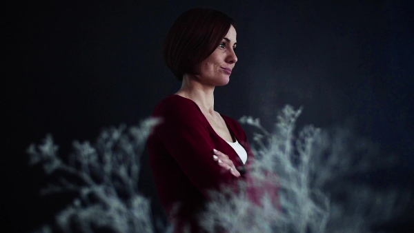 A portrait of young beautiful woman standing against dark background. Slow motion.