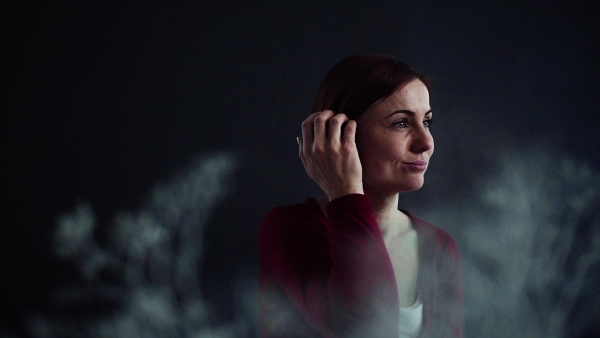 A portrait of young beautiful woman standing against dark background. Slow motion.