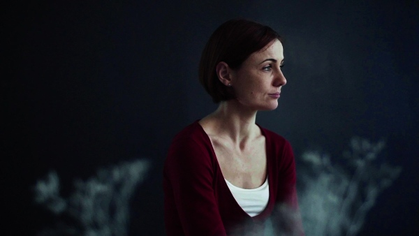 A portrait of young beautiful woman standing against dark background. Slow motion.