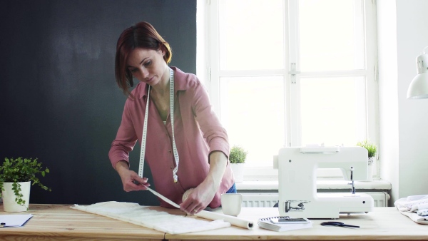 Young creative woman in a studio, working. A startup of small tailoring business.