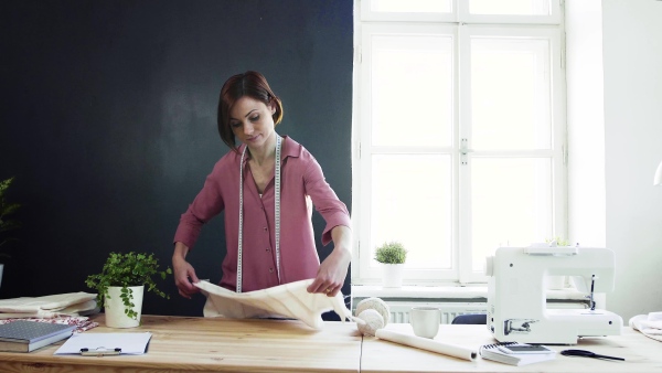 Young creative woman in a studio, working. A startup of small tailoring business.