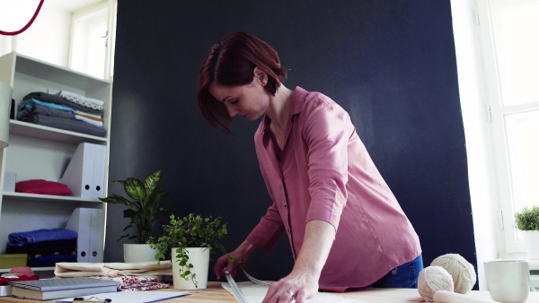 Young creative woman in a studio, working. A startup of small tailoring business.